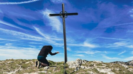 Femme en prière devant une croix